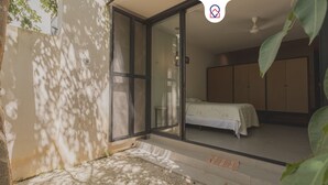A bedroom with a bed, a sliding glass door, a wardrobe, and a small balcony area with a mat. - Estudio LALO Temozon Norte Mérida (Mérida)
