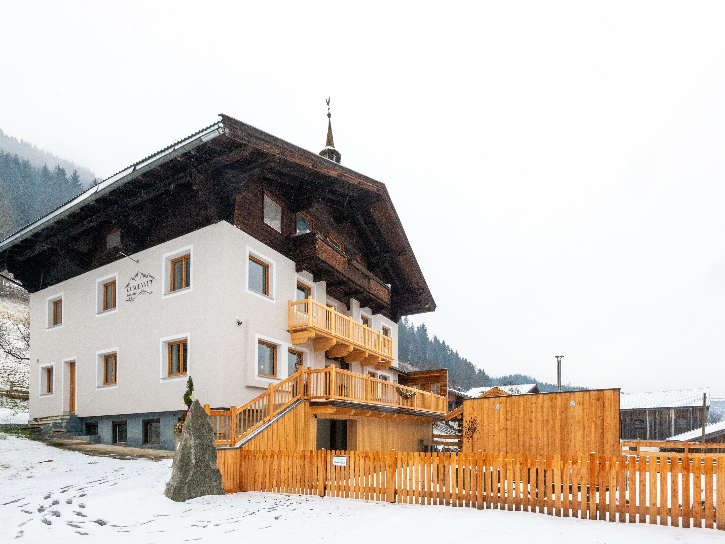 A two-story wooden building with a balcony, a wooden fence, and a snow-covered ground.