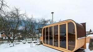A wooden cabin with large windows and a sloped roof, situated on a snow-covered deck. - Farmhouse in Bramberg With Sauna & Ski Access (Bramberg am Wildkogel)