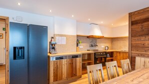 A modern kitchen with stainless steel appliances, wooden cabinetry, and a central island with seating. - Farmhouse in Bramberg With Sauna & Ski Access (Bramberg am Wildkogel)