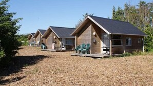 A row of wooden cabins with pitched roofs, each featuring a porch and outdoor seating. - 6 pax Camping Cabin in Rodhus, Pandarup (Pandrup)