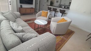 A modern living room with a sofa, armchairs, a coffee table, and a ceiling fan.