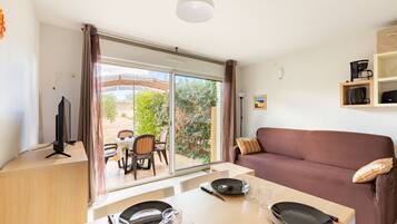 A modern living room with a sofa, dining table, and a TV.