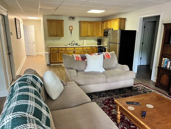 A living room with a beige sofa, a patterned throw blanket, and a wooden coffee table.