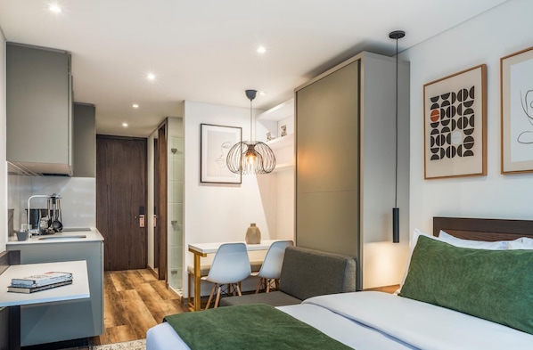 Una habitación de hotel moderna con cama, escritorio, sillas y zona de comedor.