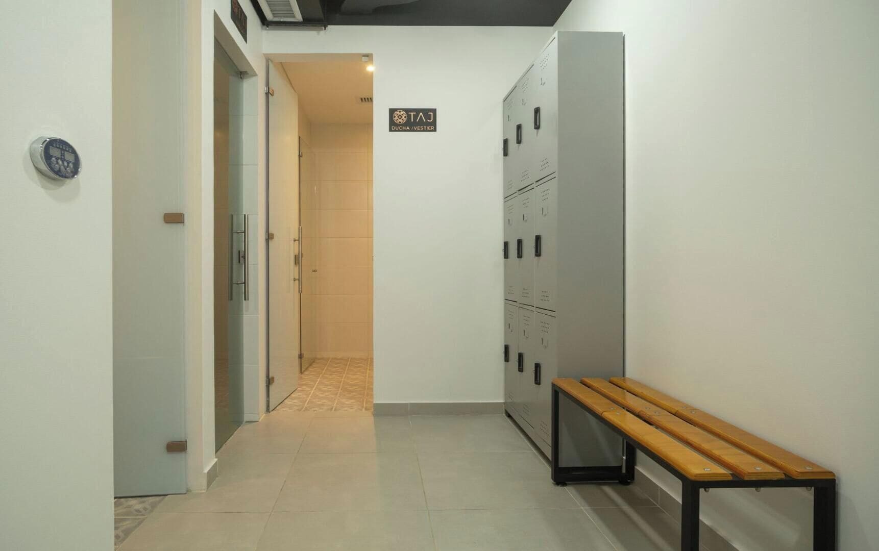 Un couloir avec des casiers, un banc et un panneau indiquant le numéro de la salle : 3.