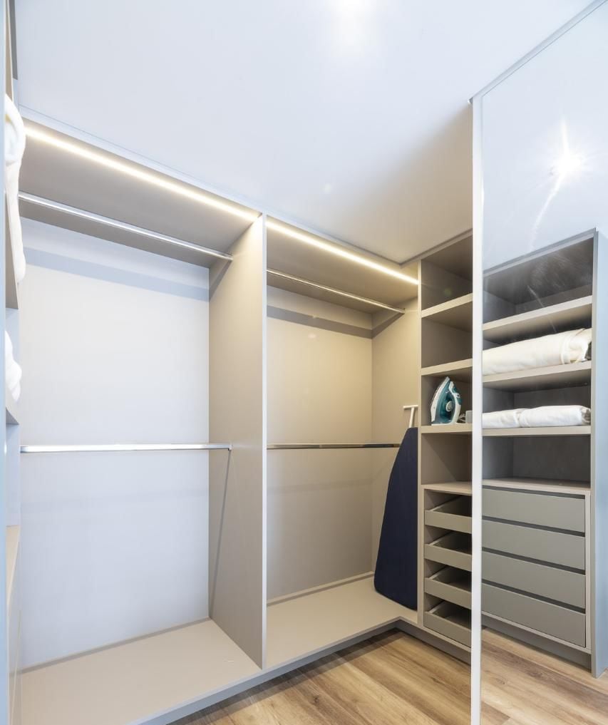 A walk-in closet with open shelving and drawers, a hanging rack, and a visible iron.