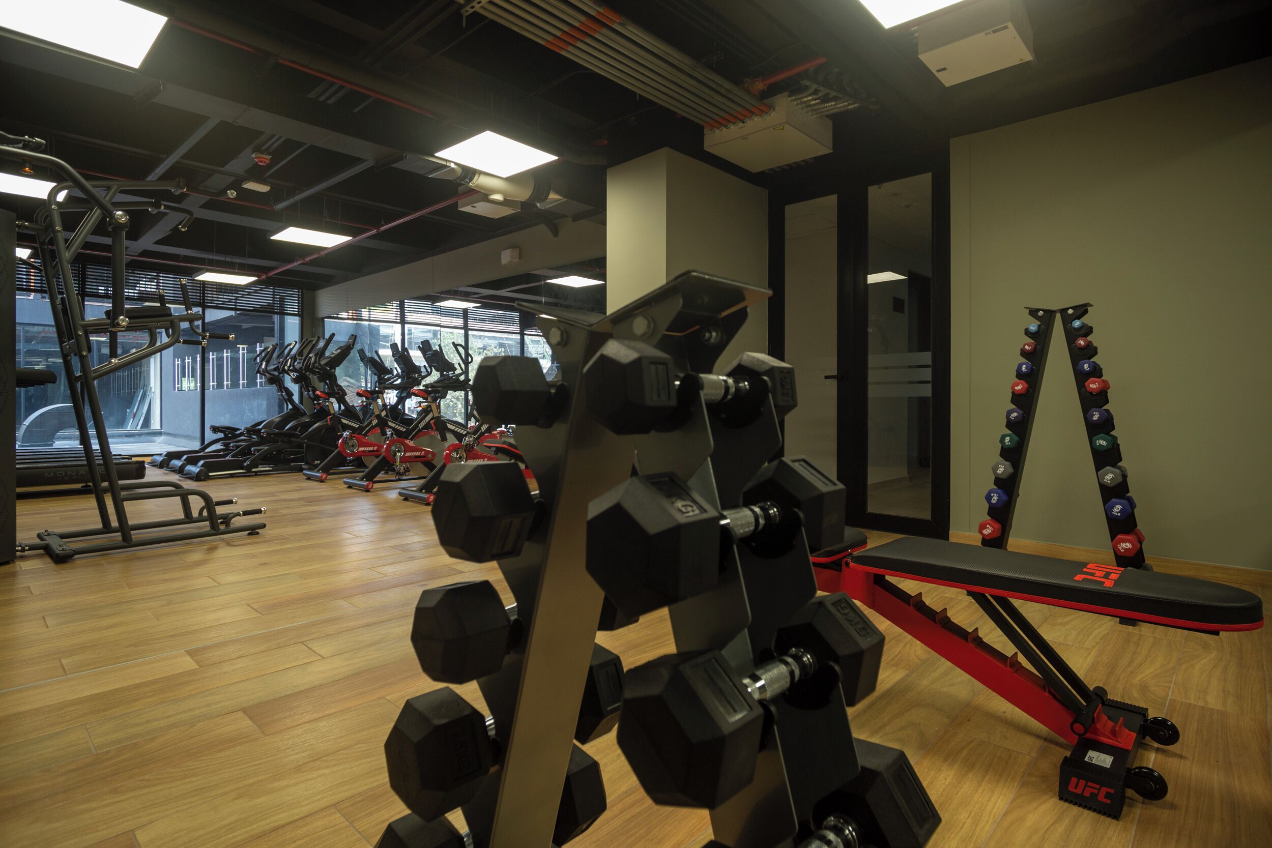 A gym with various exercise equipment, including dumbbells, a bench, and weight plates.