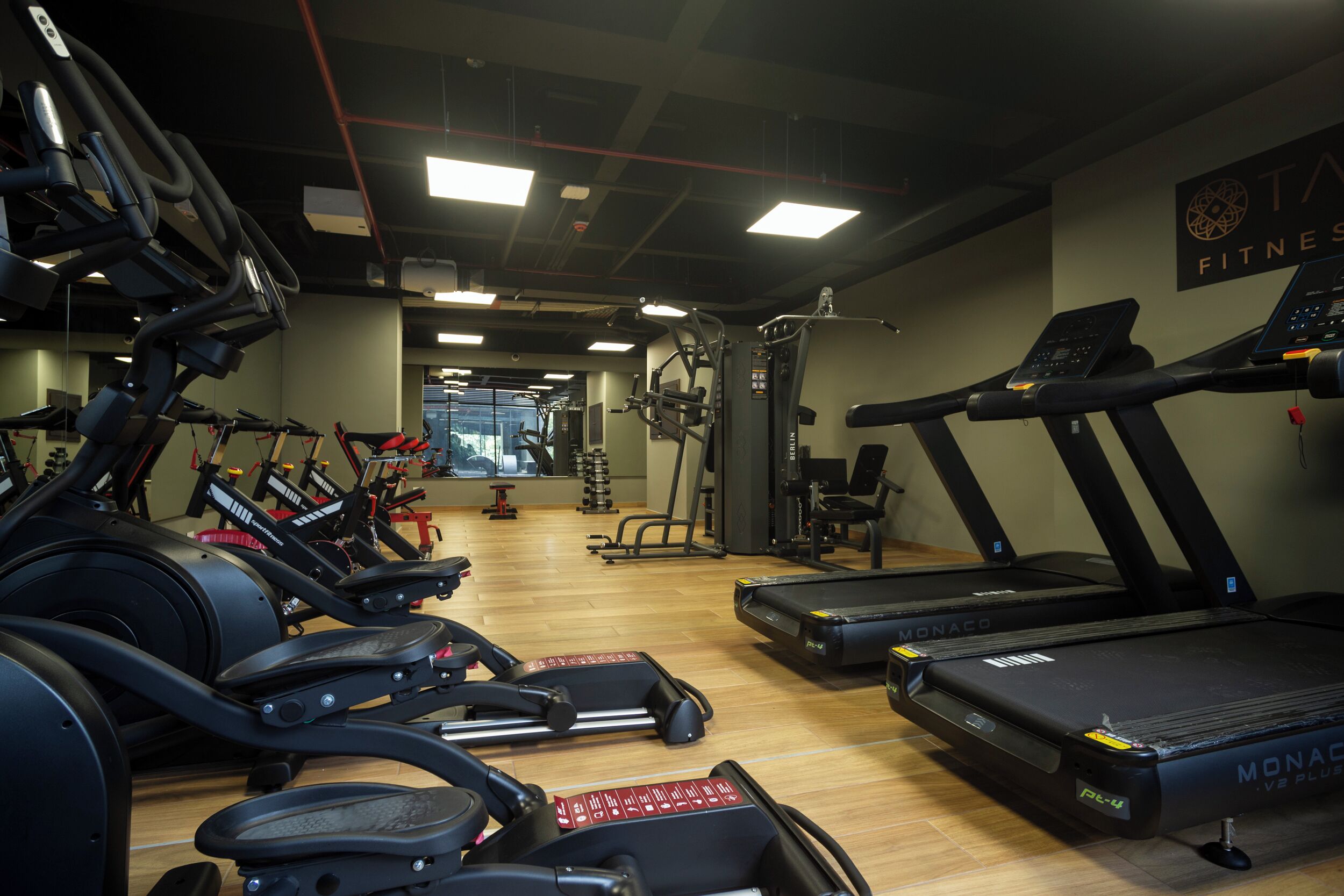Ein Fitnessstudio mit Laufbändern, Crosstrainern und Gewichtsgeräten.
