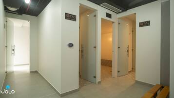 Un pasillo con varias puertas, cada una identificada con 'TAJ DUCHA VESTIER'.
