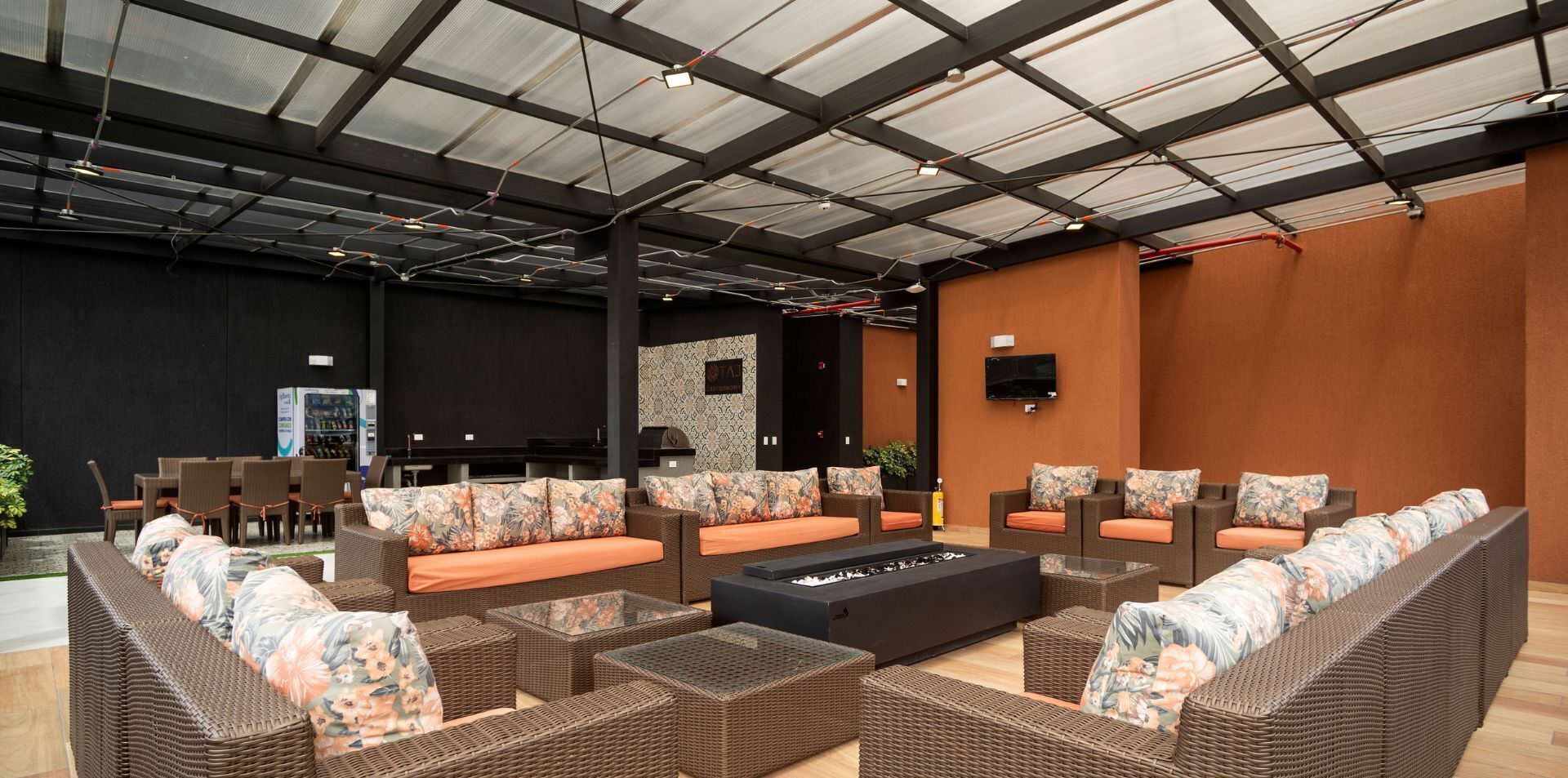 Un'ampia area lounge interna con mobili in vimini, una televisione a schermo piatto e una parete in pietra.