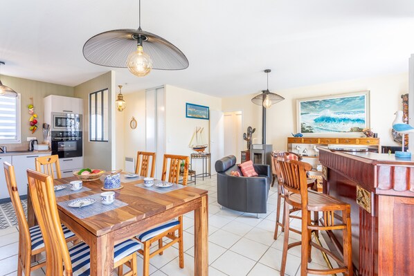 A modern kitchen with a dining area, a bar, and a living space.