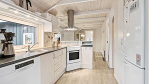Eine moderne Küche mit weißen Schränken, Edelstahlgeräten und einer Holzbeschichtung an der Decke.