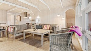 Ein geräumiger Raum mit Holzboden, einer Couch, einem Tisch und Korbstühlen.
