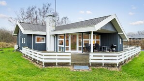 Ein modernes Haus mit einer großen Terrasse, einem Schornstein und einer Satellitenschüssel.