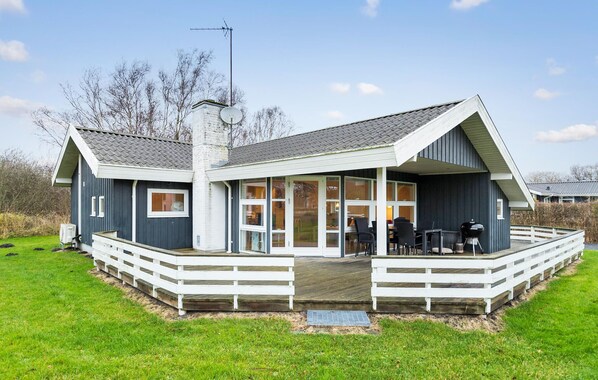 Ein modernes Haus mit einer großen Terrasse, einem Schornstein und einer Satellitenschüssel.