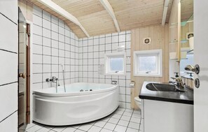 Ein modernes Badezimmer mit einer freistehenden Badewanne, einem Waschbecken mit Spiegel und einem Fenster.