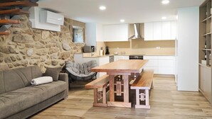 A modern living room with a stone wall, a wooden dining table, and a sofa.