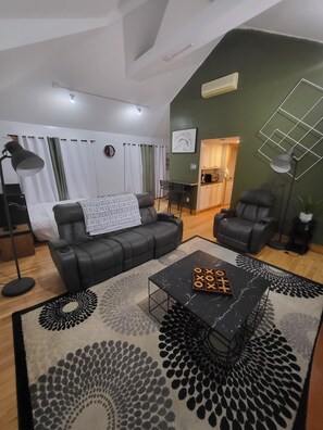 A modern living room with a black leather sofa, a coffee table with a board game, and a patterned rug. - Charming house with WiFi and AC in superb Randolph (Randolph)
