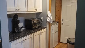 A kitchen with white cabinets, a toaster, a coffee maker, and a trash can. - Charming house with WiFi and AC in superb Randolph (Randolph)