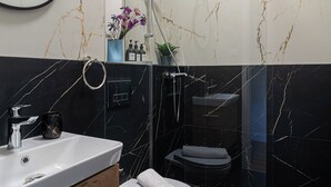 A modern bathroom with a marble vanity, a toilet, and a shower area. - Faculty of Law Studios (Bucharest)