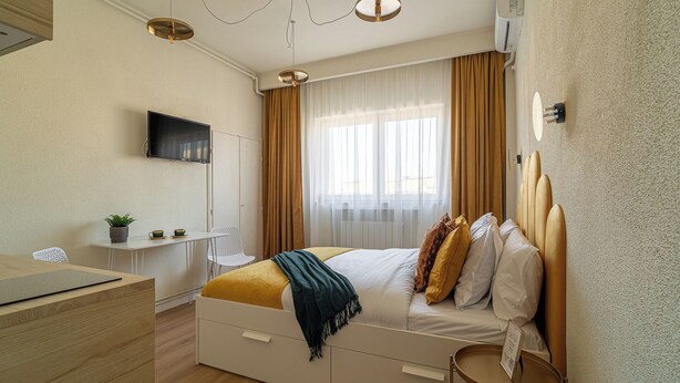 A modern bedroom with a bed, bedside table, and a TV mounted on the wall. - Faculty of Law Studios (Bucharest)