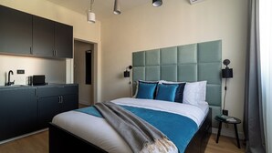 A modern hotel room with a large bed, a built-in wardrobe, a small bedside table, and a wall-mounted air conditioning unit. - Faculty of Law Studios (Bucharest)
