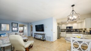 A modern living room with a sofa, a TV, and a dining area with a table and chairs. - Casa Rosa-4th Floor Gorgeous Condo (Phoenix, Arizona)
