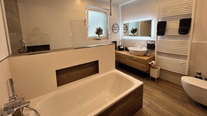 Un baño moderno con una bañera grande, un lavabo y un espejo.