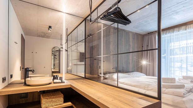 A modern hotel room with a wooden vanity, a large mirror, and a bed with white linens. - Premium Holiday Apartment With Sauna and Garden (Haus)