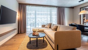 A modern living room with a sofa, a coffee table, and a TV mounted on the wall. - Premium Holiday Apartment With Sauna and Garden (Haus)