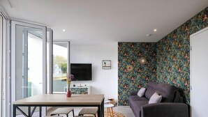 Una sala de estar moderna con sofá, mesa de comedor y televisor.