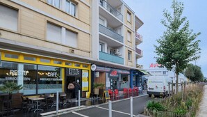 Un edificio de varios pisos con diversos comercios en la planta baja, incluyendo una cafetería y un restaurante.