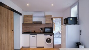 Una cocina compacta con lavadora, microondas y un refrigerador pequeño.