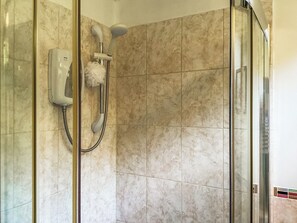 Une douche équipée d’un pommeau de douche à main et d’un panneau de commande fixé au mur.