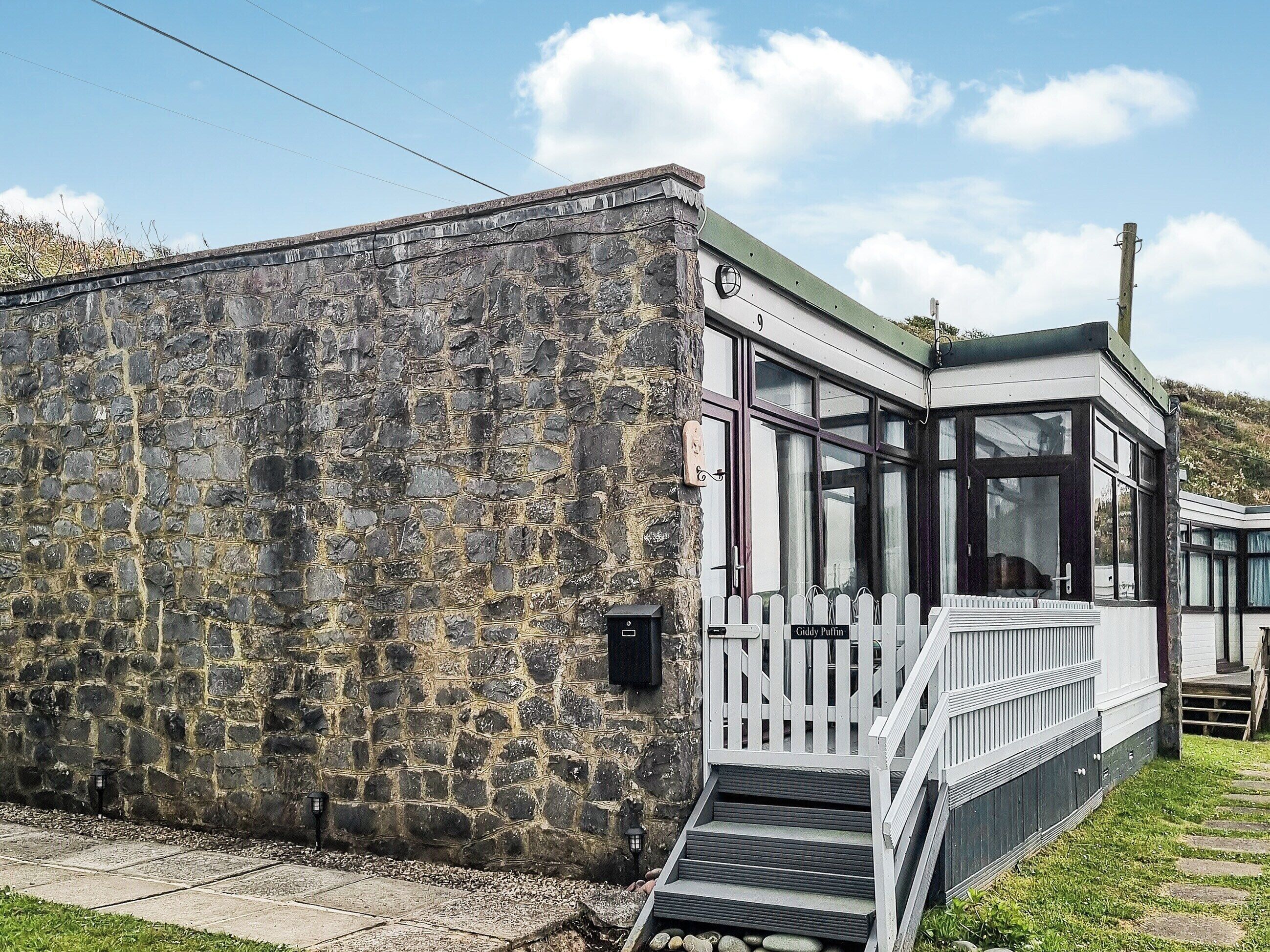 A stone building with a white porch and a staircase leading to a door.