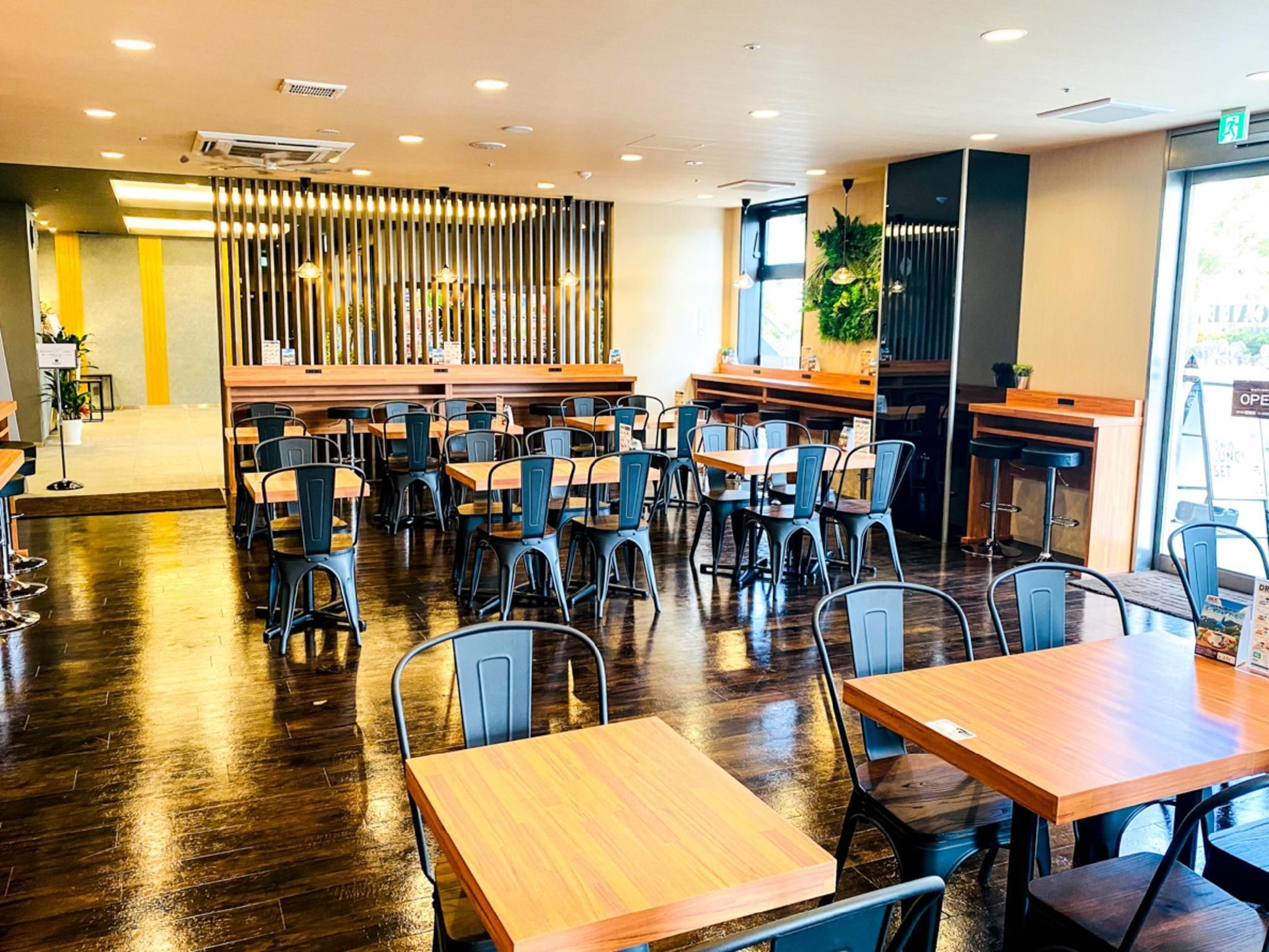 A modern restaurant interior with wooden tables and chairs, a central bar area, and a decorative vertical panel.