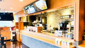 A restaurant with a counter, menu boards, and kitchen equipment.