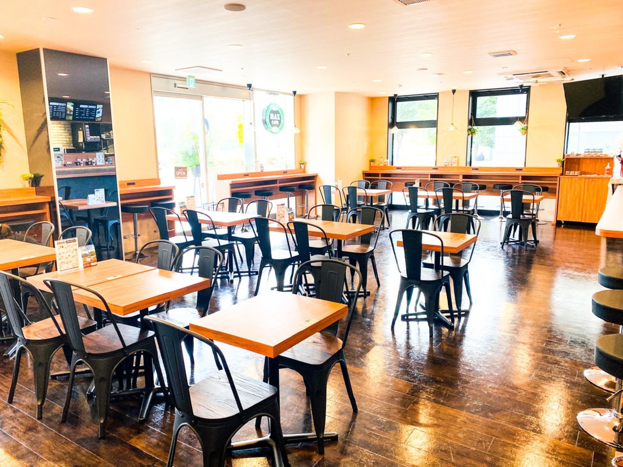 A spacious restaurant with wooden tables and chairs, a counter with a menu, and large windows allowing natural light.