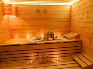 A wooden sauna with benches, candles, towels, and a bucket. - Hotel Livemax Premium Nagano Ekimae (Nagano)