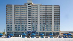 A high-rise hotel with multiple balconies and a beach area with sun loungers and umbrellas. - Two Bedroom, Ocean Front, Luxury Condo, Panama City Beach, Florida 4253341 (Panama City Beach)