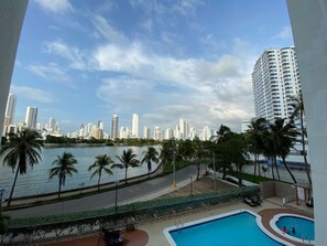 A view of a city skyline with tall buildings, a body of water, and a pool area with palm trees. - Apartaestudio Con Encanto en Cartagena (Cartagena)