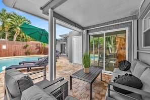 A covered patio with a pool, outdoor furniture, and a sliding glass door leading to a backyard. - Sunny Days Getaway, 5BD Heated Pool Family Home! (Fort Lauderdale)