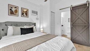 Un dormitorio con cama, cabecera, decoración en la pared y una puerta corredera estilo granero.
