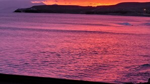 A sunset over a body of water with a distant shoreline. - Noda House Tarajalejo (Tarajalejo)