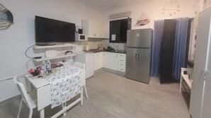A compact kitchen with a microwave, refrigerator, and a flat-screen TV. - Noda House Tarajalejo (Tarajalejo)