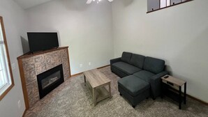 A living room with a fireplace, a sofa, a coffee table, and a ceiling fan. - North Liberty Townhouse (North Liberty)