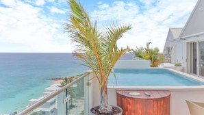 A pool area with a view of the ocean, a palm tree, and a wooden deck. - Sapphire Beachfront Penthouse (Lowlands)
