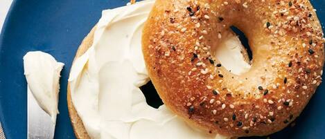 A bagel with cream cheese and sesame seeds on a blue plate.