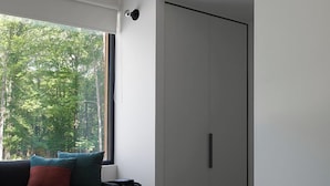 A modern bedroom with a large window, a black sofa, a green bed, and a white wardrobe. - Coldbrook Bed and Breakfast (Bearsville)